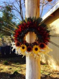 Wreath with lavender sprigs, chile pequin, local juniper, homegrown Indian corn, sand dried zinnias and wild sunflowers on a corn husk wreath base.